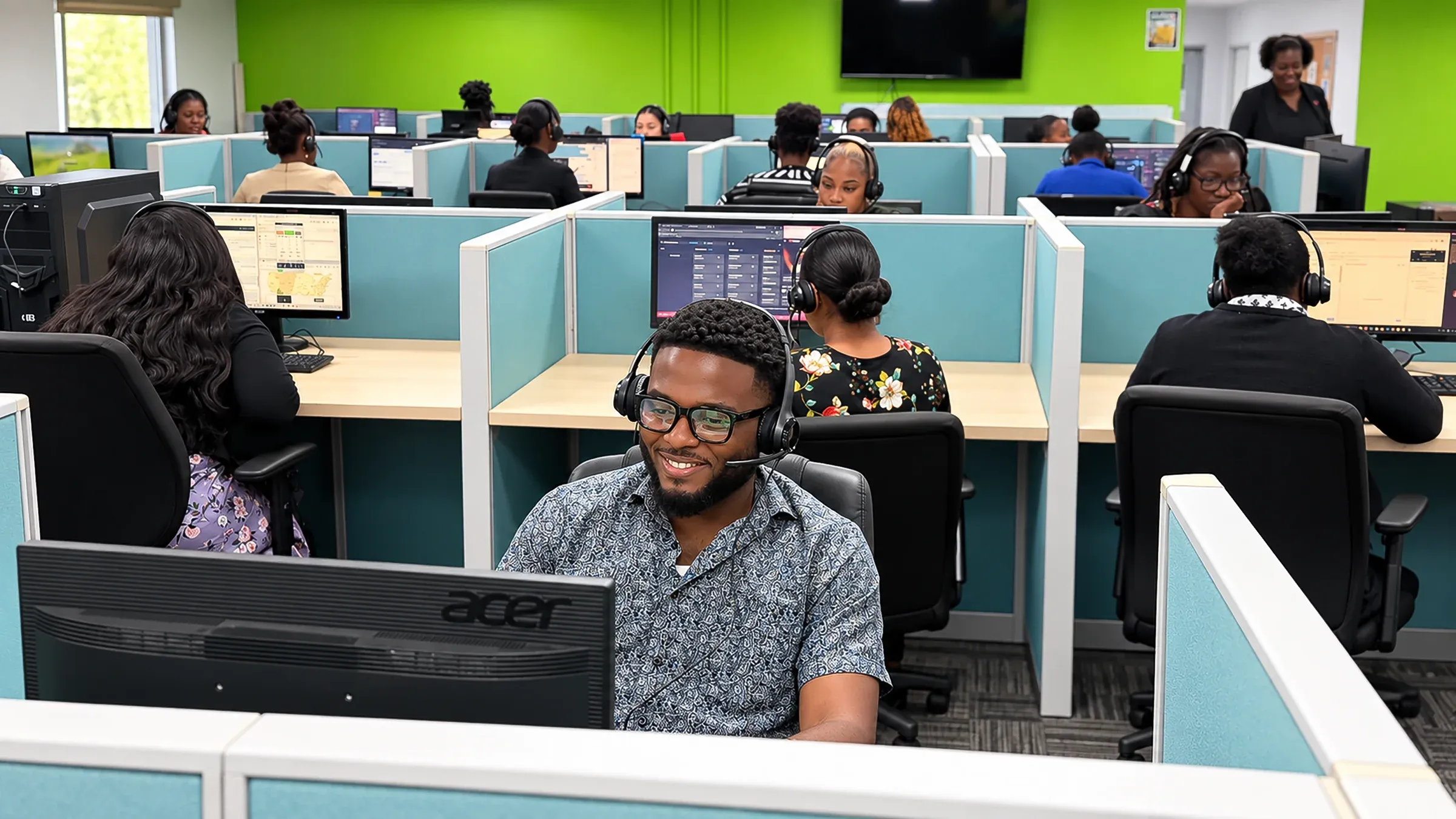 CallServ agents at work on the Trinidad operations floor, wearing headsets at partitioned desks with performance software on their screens.